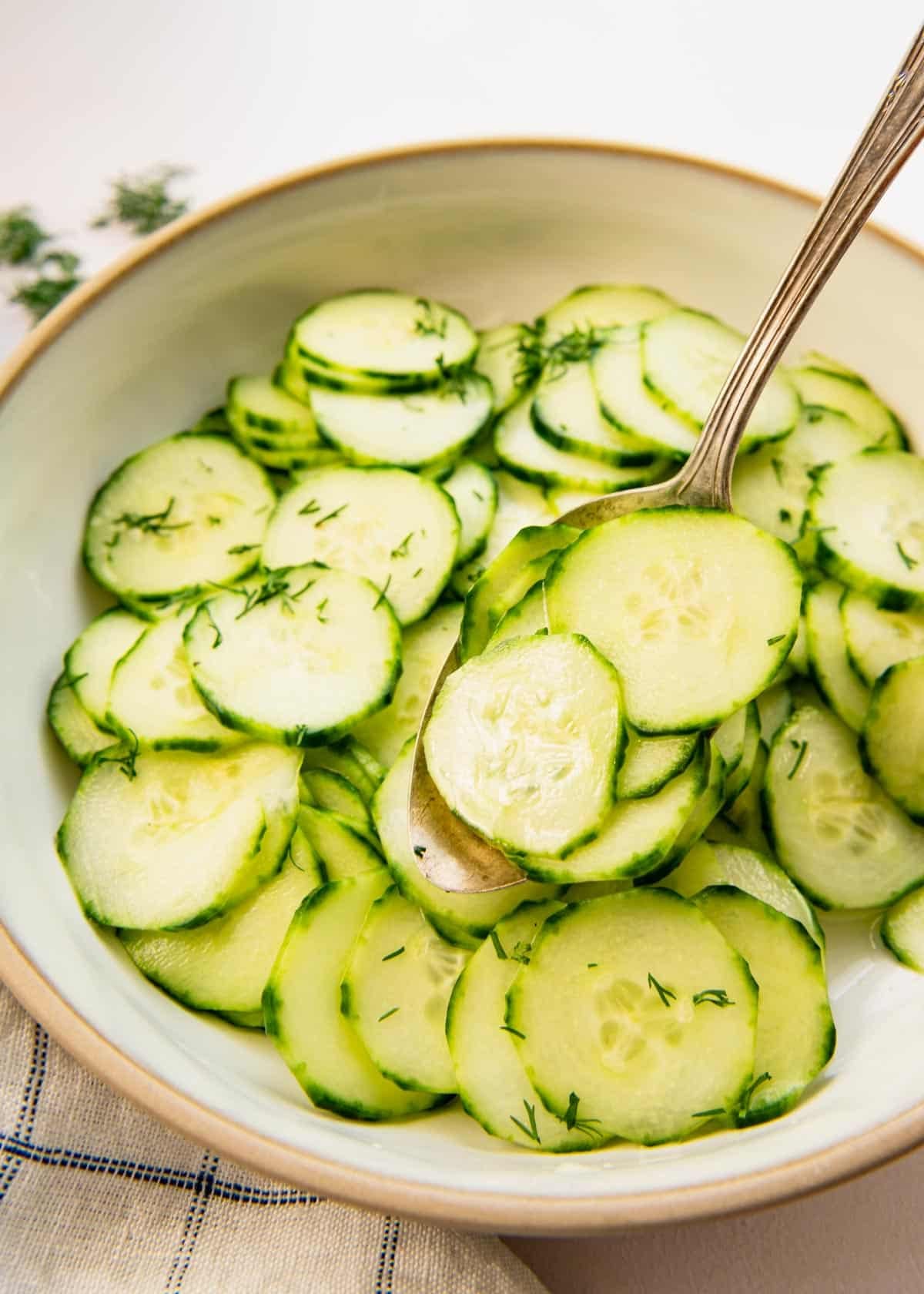 Spoon serving a cucumber salad with vinegar.