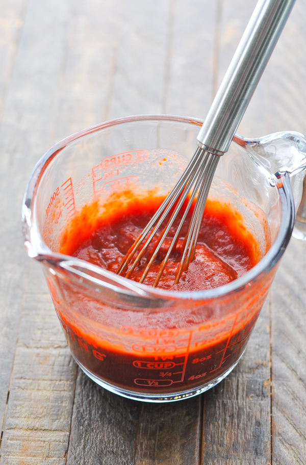 Red wine and tomato paste mixed together with a whisk in a glass measuring cup -- the tomato-based sauce for a beef ragu.