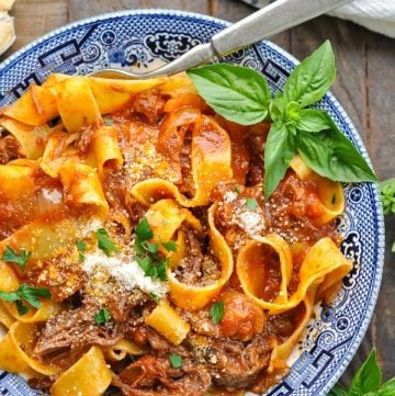 Close overhead shot of slow cooker beef ragu recipe served over pasta in a blue and white bowl