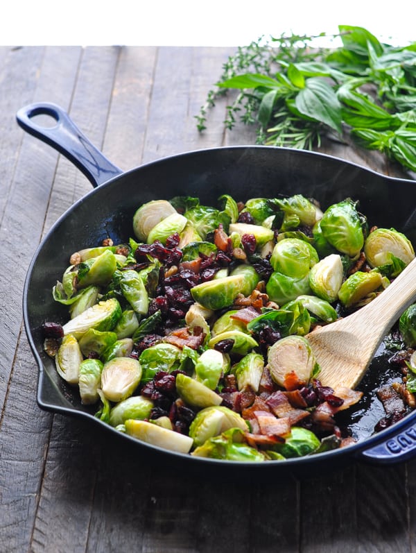 Stirring cranberries and bacon into a skillet with brussels sprouts