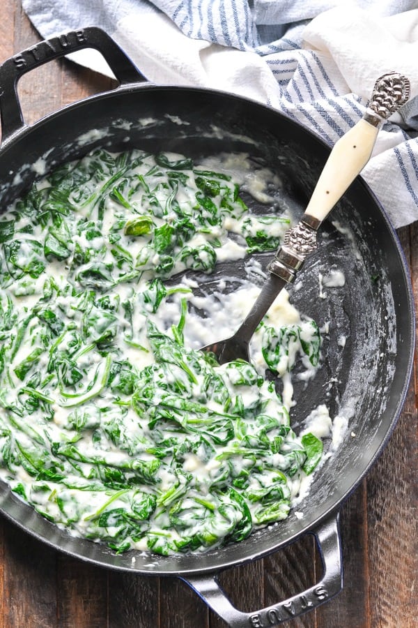 Long overhead shot of creamed spinach in a cast iron skillet