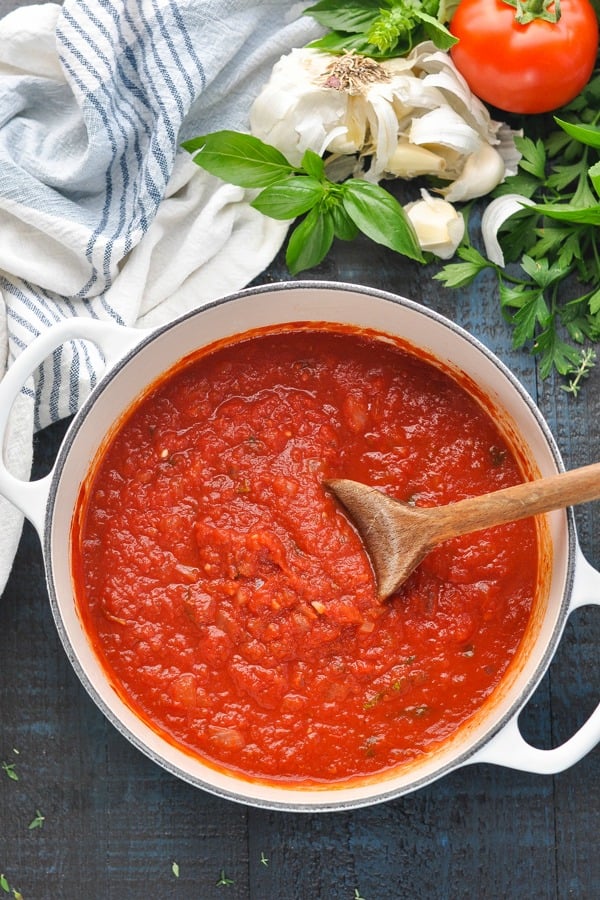 Overhead shot of a pot of easy marinara sauce recipe with a wooden spoon for stirring