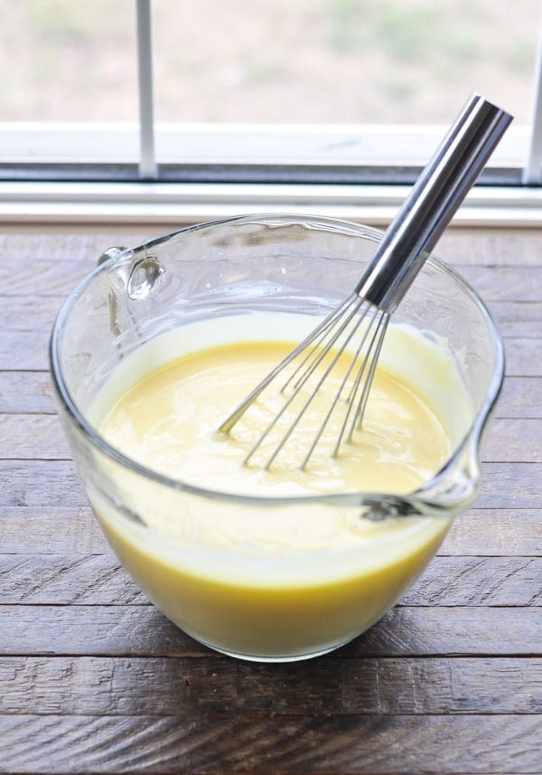 Vanilla pudding in a glass mixing bowl with whisk