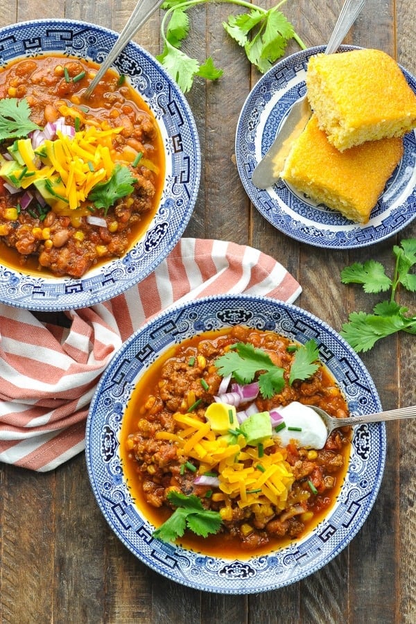 Overhead shot of two bowls of pumpkin chili with cornbread on the side