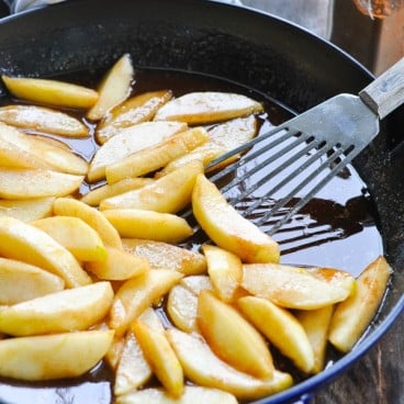 Close front shot of fried apple slices in a skillet