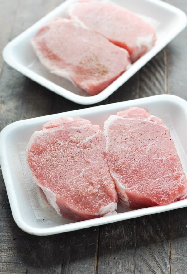 Raw thick cut boneless pork chops on tray