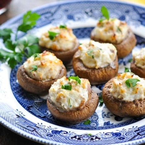 Close up front shot of crab stuffed mushrooms on a blue and white plate