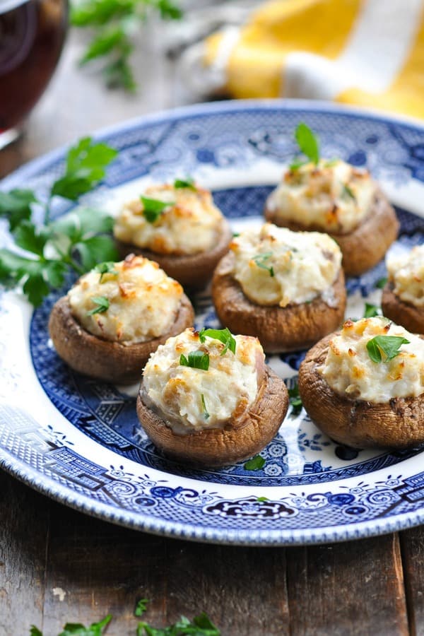 Close up front shot of crab stuffed mushrooms on a blue and white plate