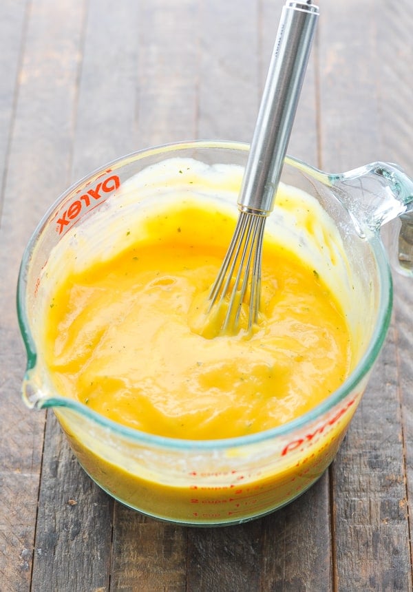 Cheese sauce in a glass measuring cup with whisk