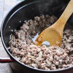 Ground beef onion and garlic in a pot with a wooden spoon