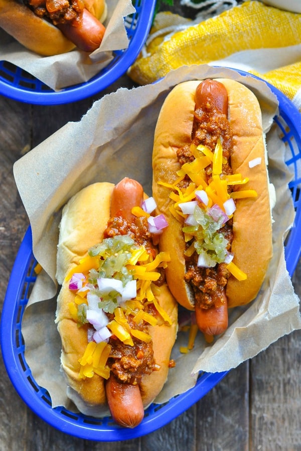 Hot dogs topped with hot dog chili cheese and onion in a serving basket