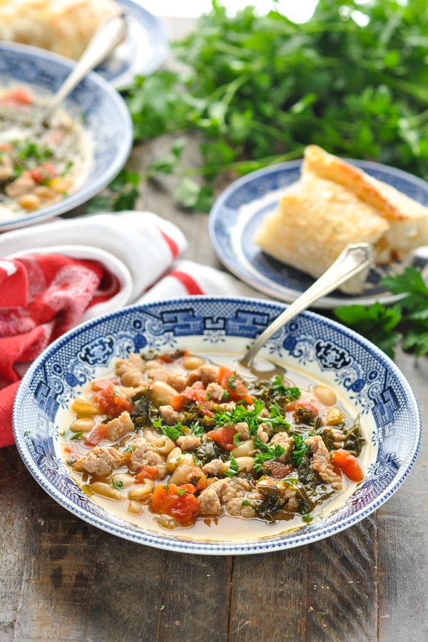 Front image of Tuscan White Bean Soup with Sausage and kale on a wooden surface