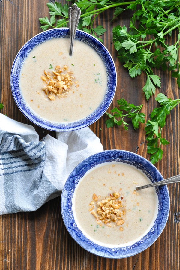 Overhead image of two bowls of peanut soup garnished with chopped peanuts