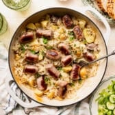 Square overhead shot of a cast iron pan full of bratwurst and sauerkraut and potatoes.
