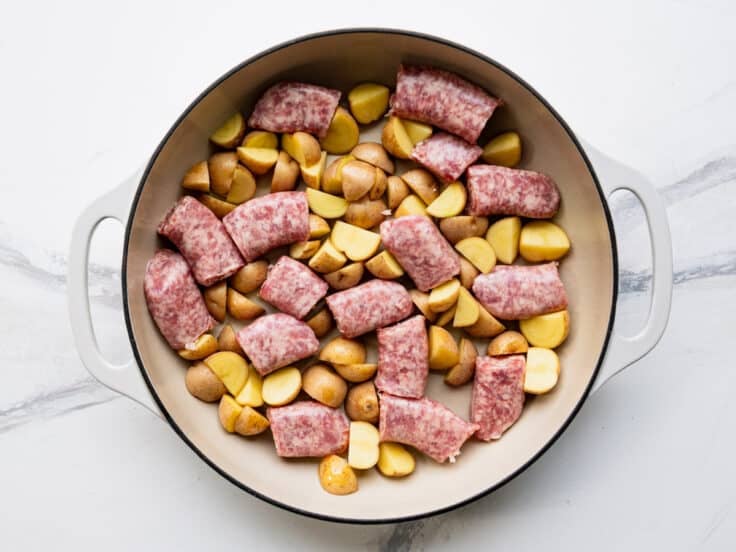 Brats and potatoes in a cast iron pan.