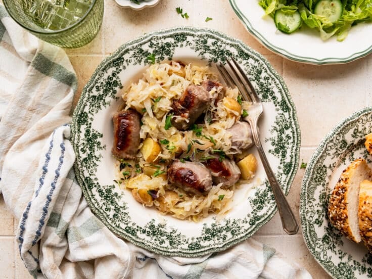 Horizontal overhead shot of a bowl of brats with sauerkraut and potatoes.