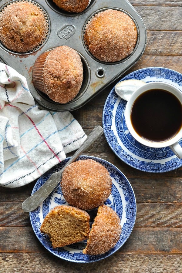 Long overhead shot of brown sugar cinnamon muffins on a wooden table with a cup of coffee