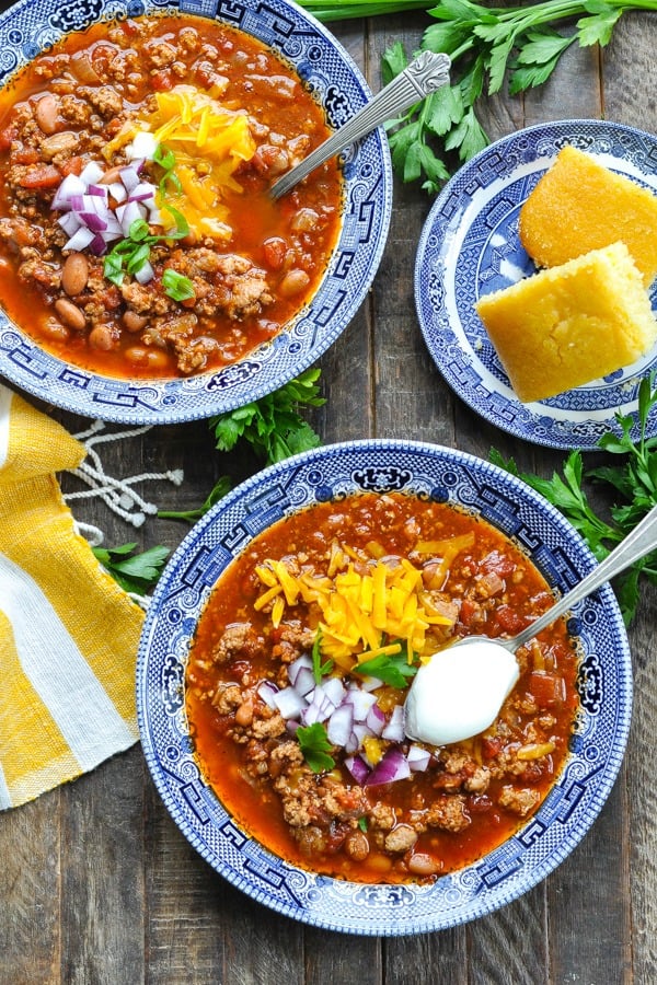 Overhead shot of two bowls of pressure cooker turkey chili with cornbread and toppings