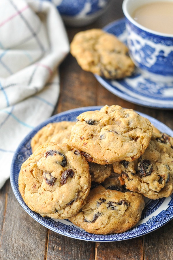 A plate full of homemade oatmeal raisin cookies sits on a wooden tabletop.