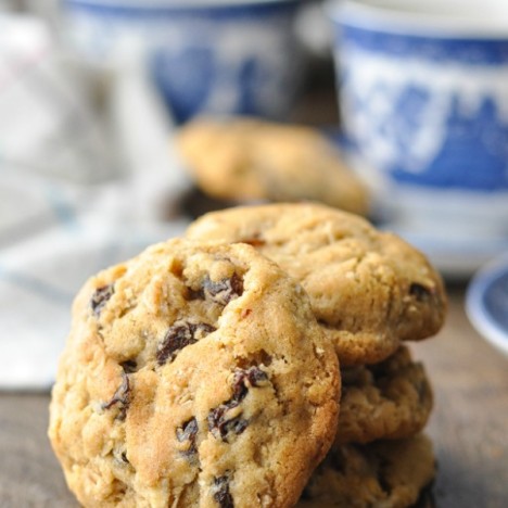 Close up shot of an oatmeal raisin cookie propped up against a stack of other cookies