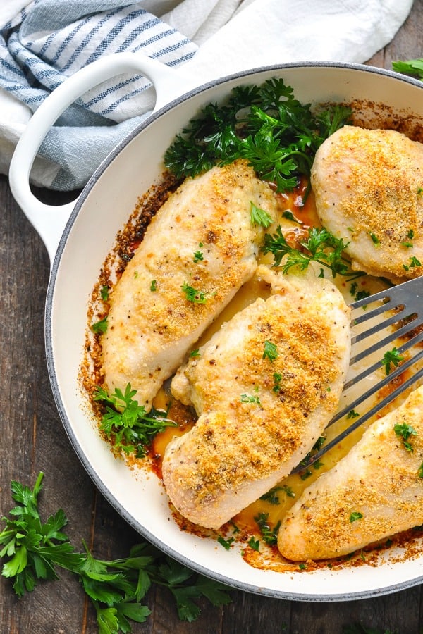 Overhead shot of parmesan crusted chicken in a white pan with spatula