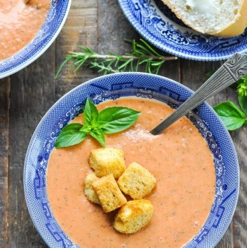 Close overhead shot of a bowl of Tomato Bisque topped with fresh basil and croutons
