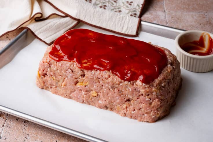 Spreading ketchup on top of the ground turkey. meatloaf before baking.