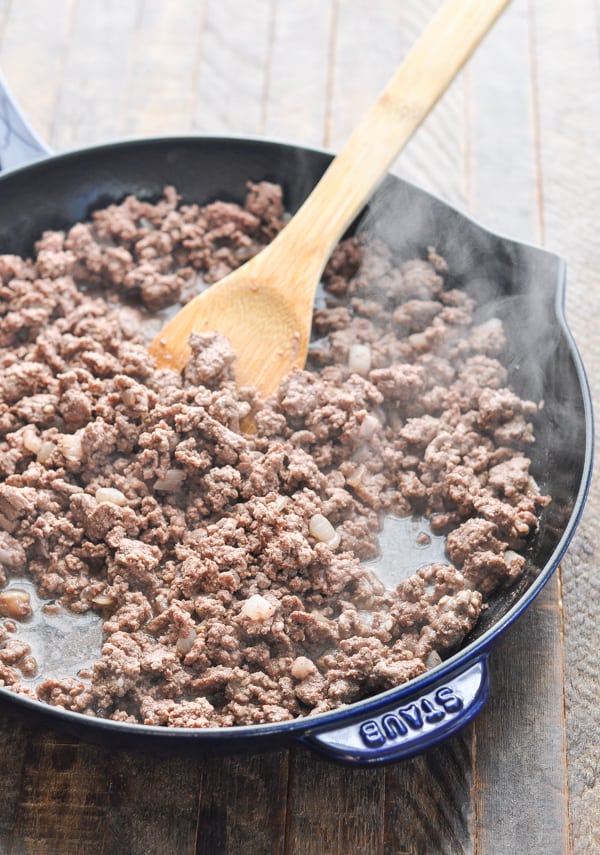 Process shot of browning ground beef and onion in a skillet