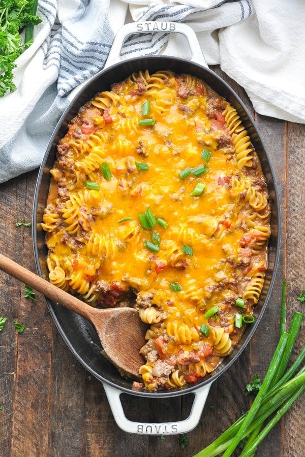Overhead shot of a wooden spoon in a cast iron baking dish full of cheeseburger casserole