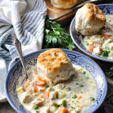 Front shot of chicken pot pie soup in a blue and white bowl on a wooden surface