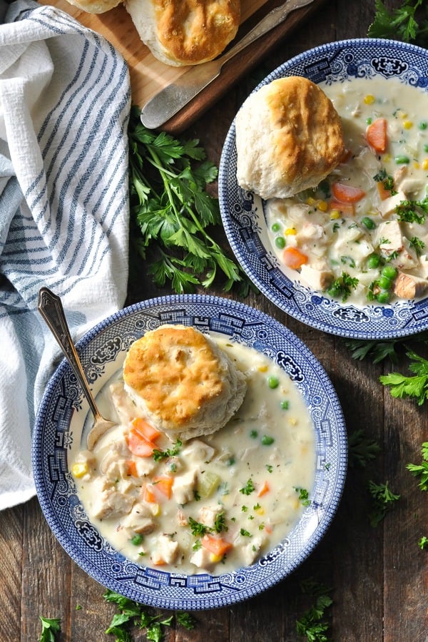 Overhead shot of chicken pot pie soup with biscuits in bowls