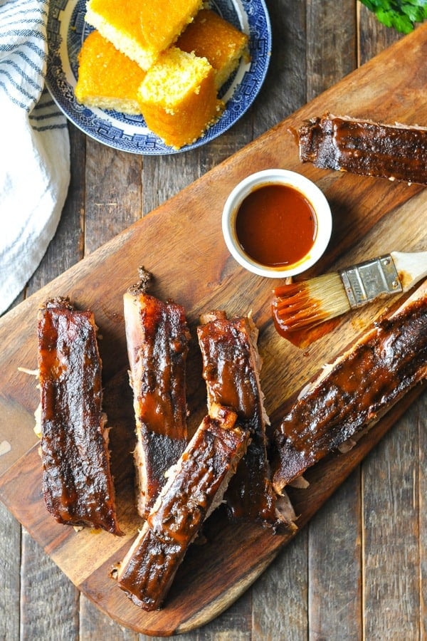 Close overhead shot of Crock Pot Ribs on a cutting board with basting brush and barbecue sauce