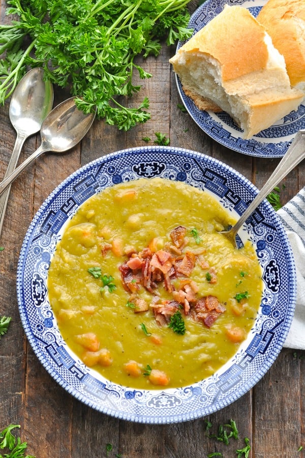 Overhead shot of a bowl of split pea soup with bacon on top and a side of bread