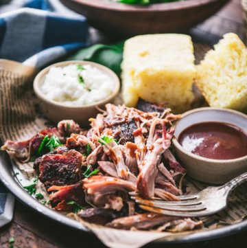 Square featured close up image of a tray of mississippi pulled pork with cornbread and coleslaw