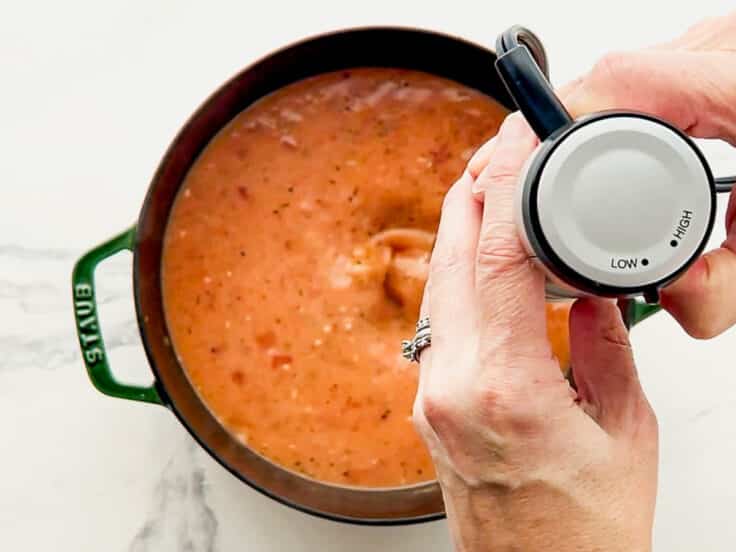 Pureeing the soup with an immersion blender.