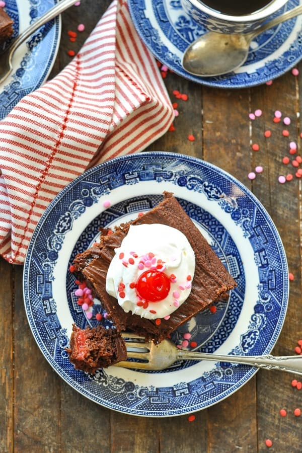 Overhead shot of a plate of chocolate cherry cake on a wooden table