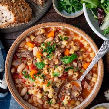 Overhead image of a bowl of pasta fagioli soup with a side of bread.