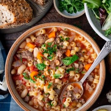 Overhead image of a bowl of pasta fagioli soup with a side of bread.