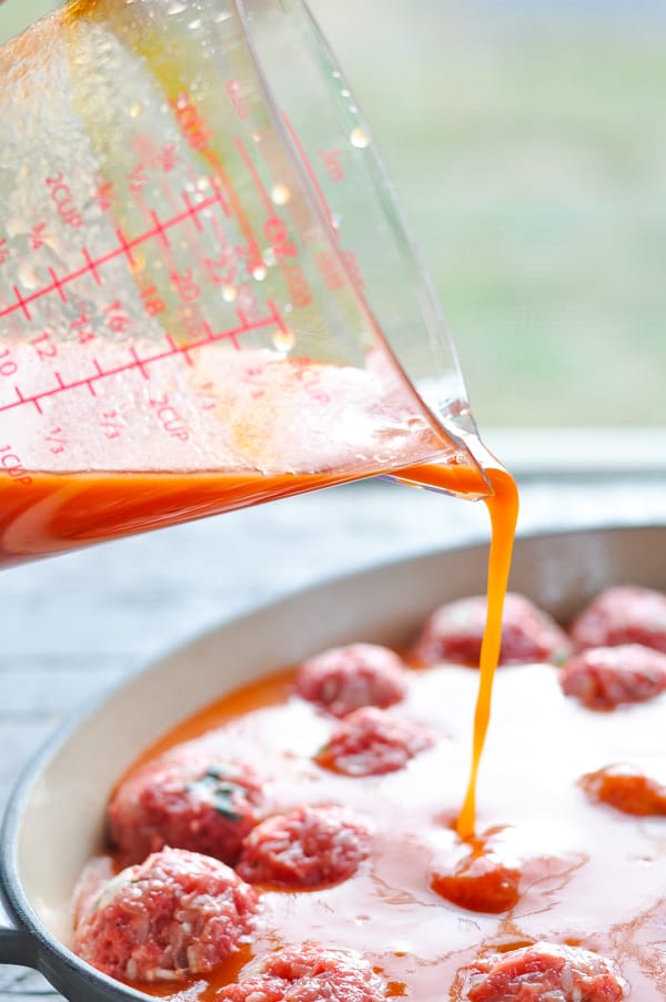 Pouring tomato sauce mixture over porcupine meatballs
