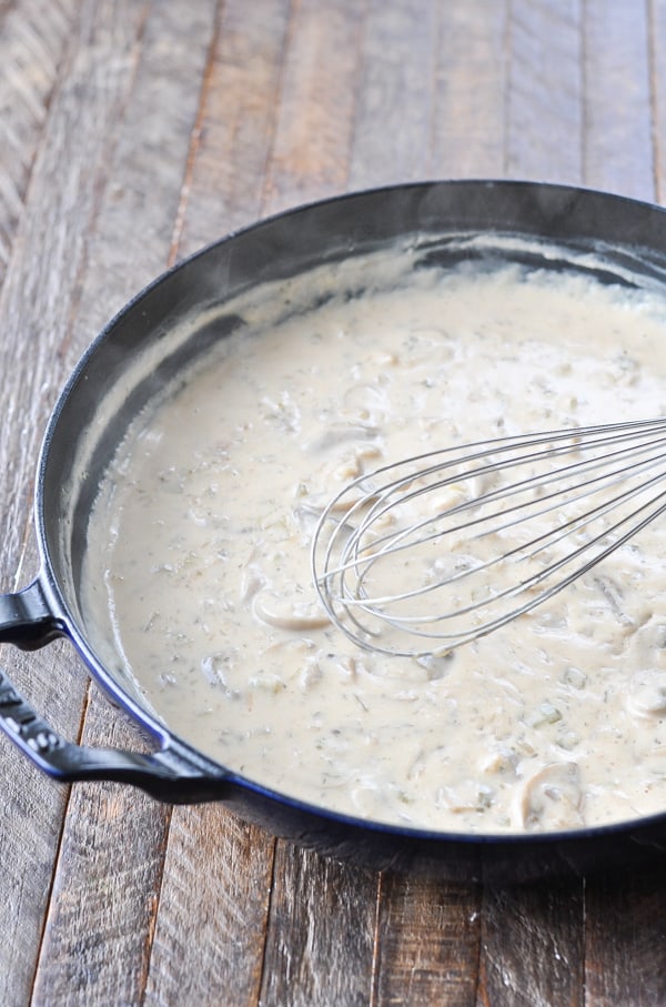 Whisking a creamy mushroom sauce in a cast iron skillet