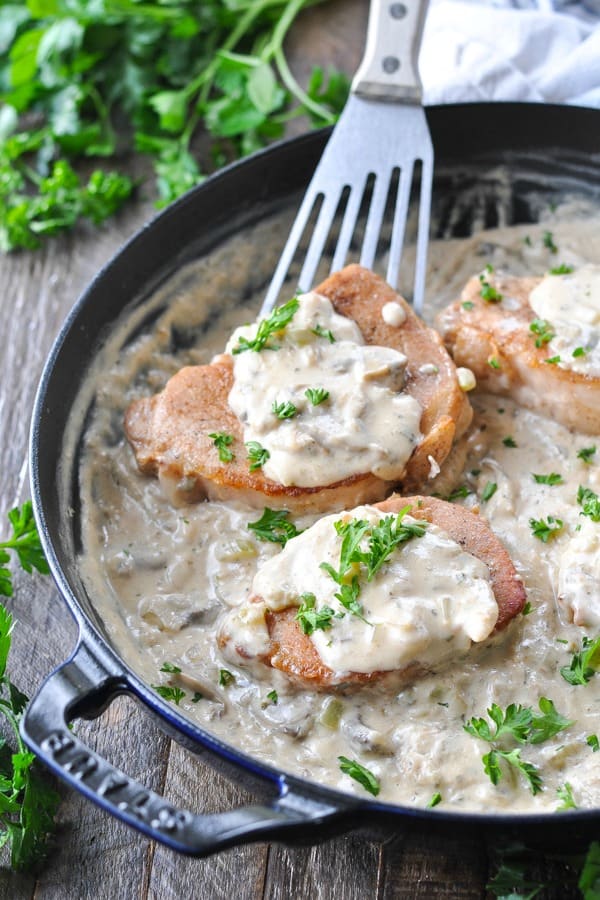 Spatula serving pork chops and rice with creamy sauce