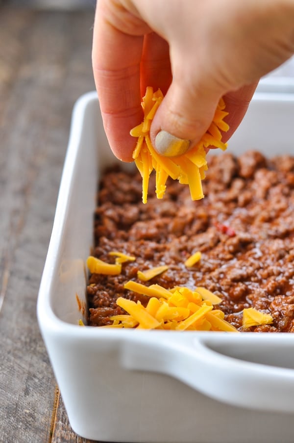 Sprinkling cheese on top of sloppy joe filling for casserole