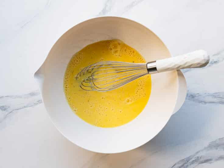 Whisking together the egg custard in a bowl.