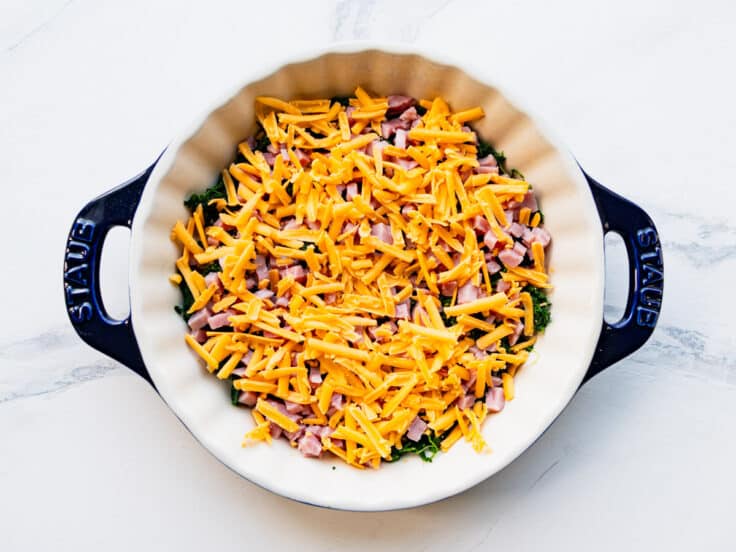 Layering the spinach, ham, and cheese in the pie dish.