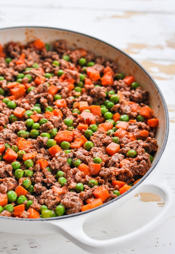 Front shot of ground beef filling for cottage pie in a white cast iron skillet