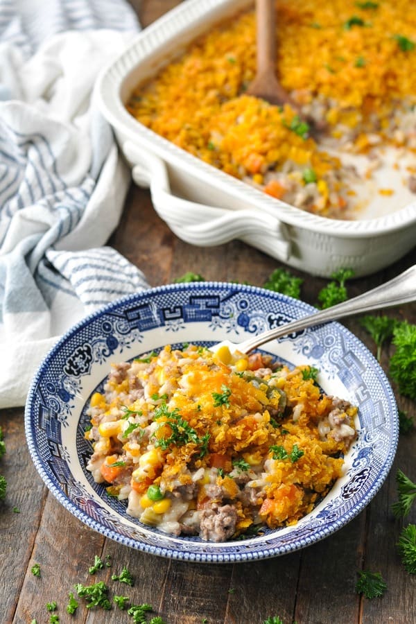 Front shot of hamburger casserole with rice on a wooden table with a baking dish in the background