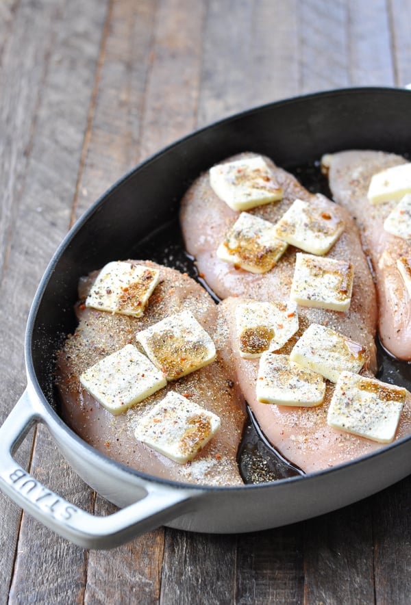 Chicken breasts in a baking dish with butter and seasoning on top