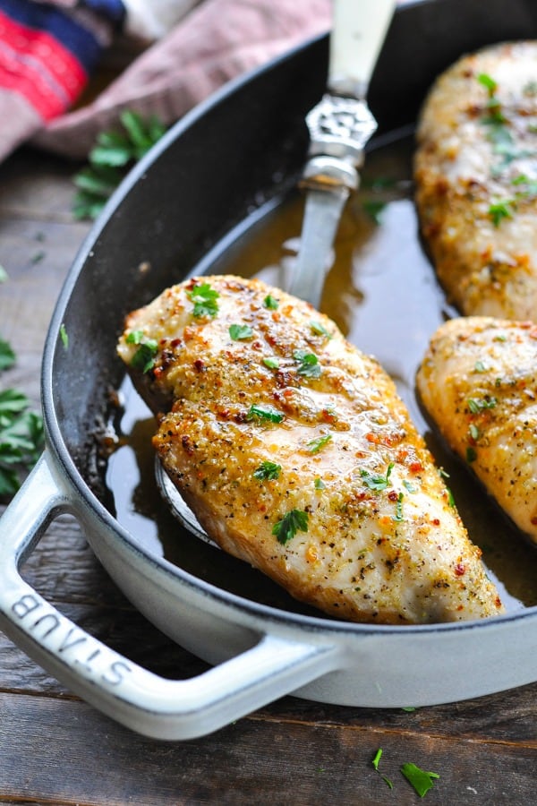 Baked boneless skinless chicken breasts with seasoning in a baking dish