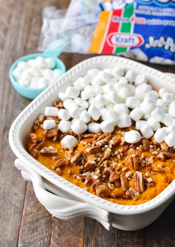 Putting marshmallows and pecans on top of sweet potato casserole