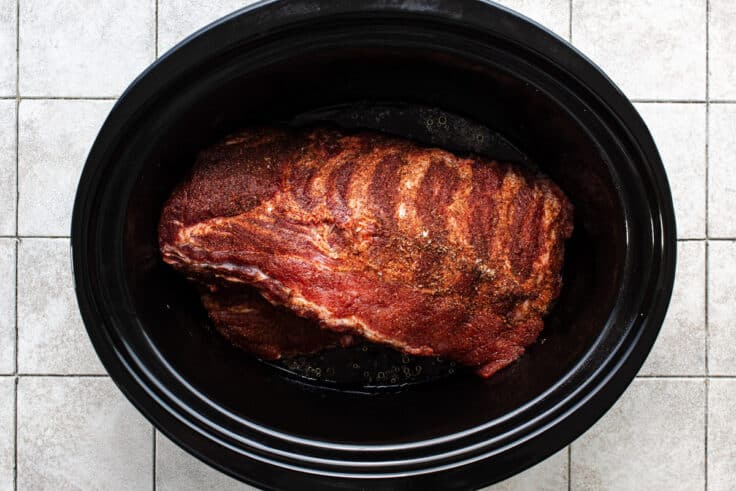 Seasoned baby back ribs in a slow cooker.